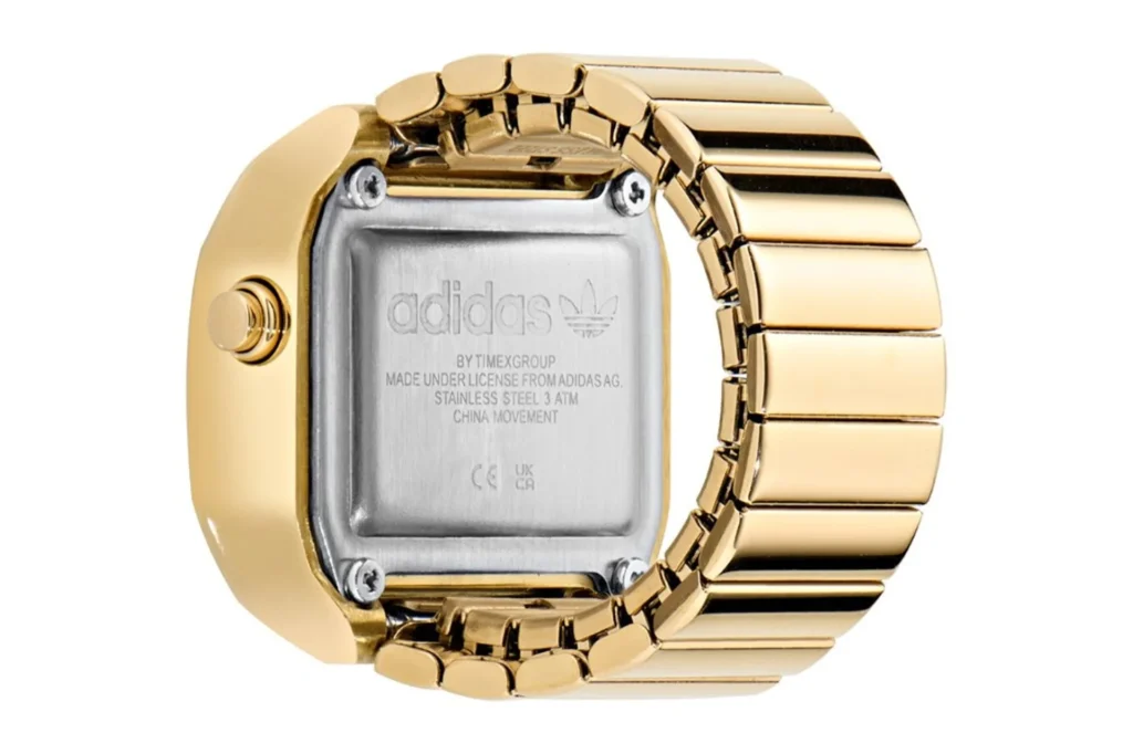 Rear view of gold-tone adidas Digital Two ring showing stainless steel case back with Timex Group and adidas licensing marki…