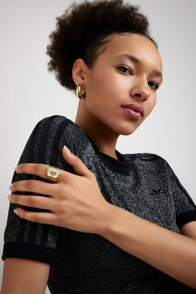 Woman wearing a gold-tone adidas Digital Two ring with digital display and black glitter adidas tee.