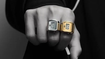 adidas Digital Two ring watches in silver and gold on a fist with a black adidas Superstar sneaker and track jacket.