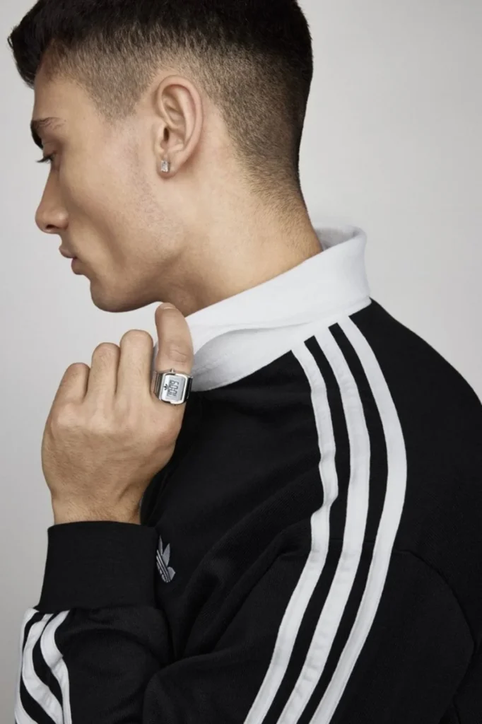 Side profile of a man in a black adidas track jacket wearing a silver-tone adidas Digital Two ring on his finger.
