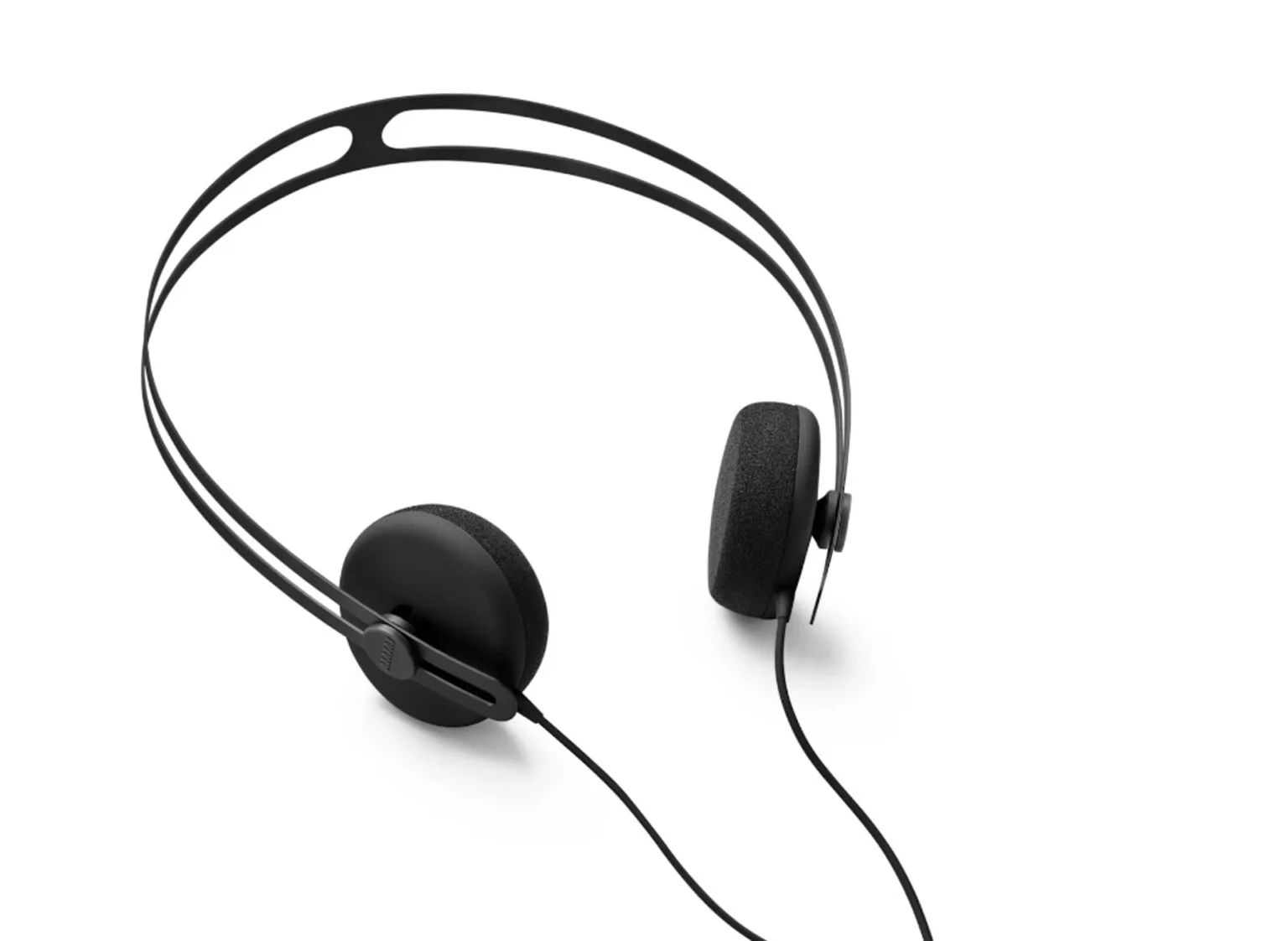 AIAIAI Tracks on-ear headphones three-quarter view on white: thin split headband, circular pads, AIAIAI branding on slider,…