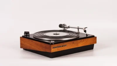 Close-up of Beogram 1000 silver tonearm over platter with black rubber mat and wood base, shallow depth of field.