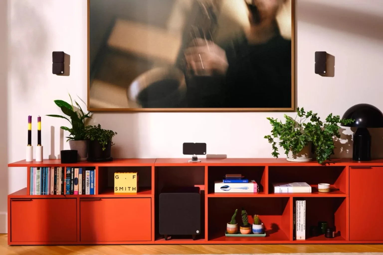 Cambridge Audio Minx black satellite speakers and subwoofer in a modern living room with a red modular sideboard, plants, bo…