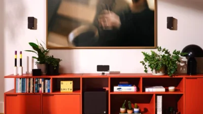 Cambridge Audio Minx black satellite speakers and subwoofer in a modern living room with a red modular sideboard, plants, bo…