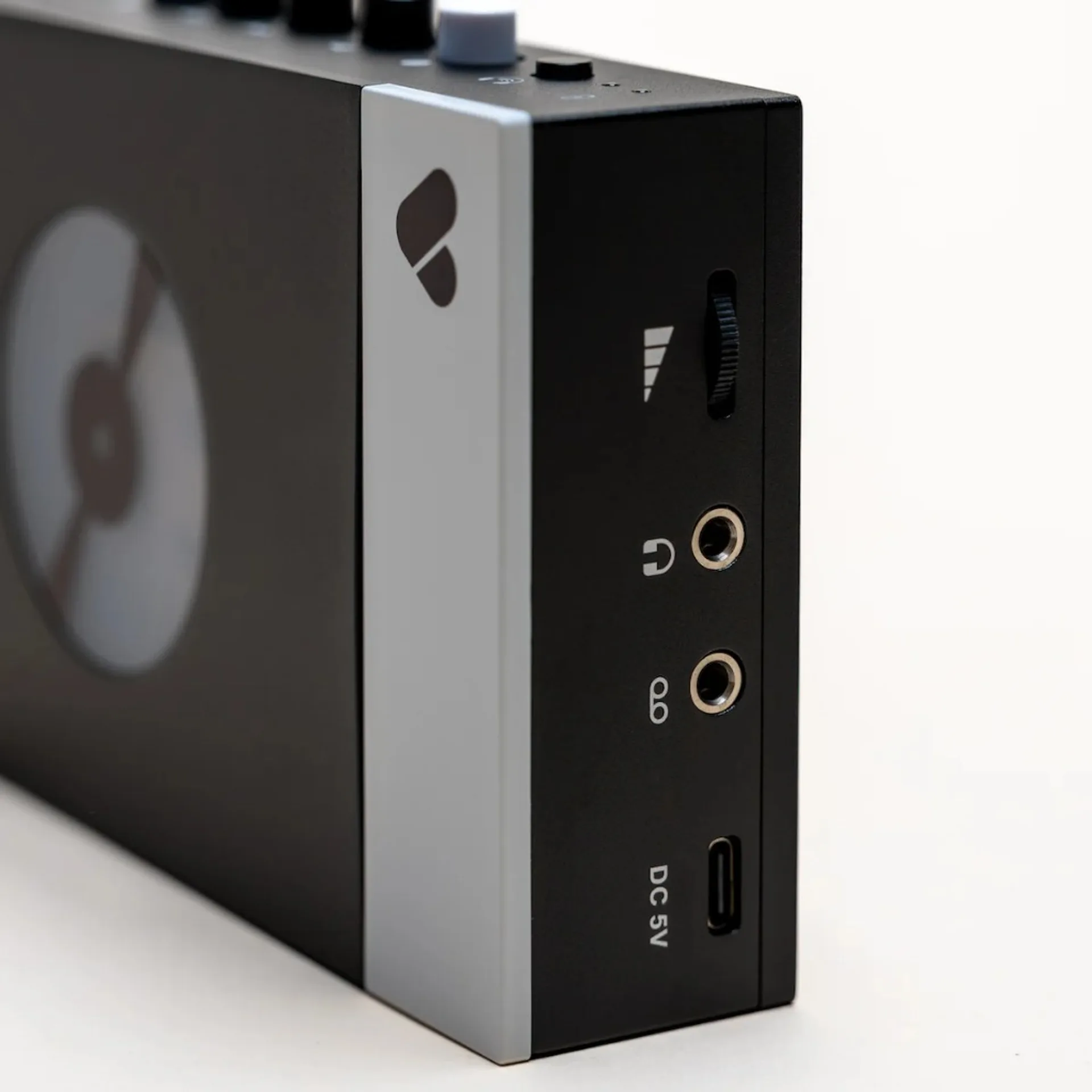 Angled side view: Discogs logo on silver strip, volume wheel, 3.5 mm headphone and line jacks, USB-C DC 5V charging, partial cassette window.