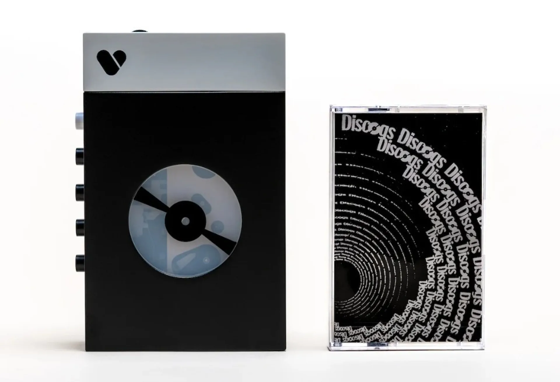 Discogs x We Are Rewind limited player in matte black and silver next to Discogs-branded cassette in clear case with spiral artwork.