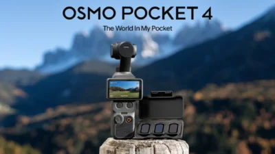 DJI Osmo Pocket 4 on a wooden post with ND filter case against blurred mountain landscape and blue sky.