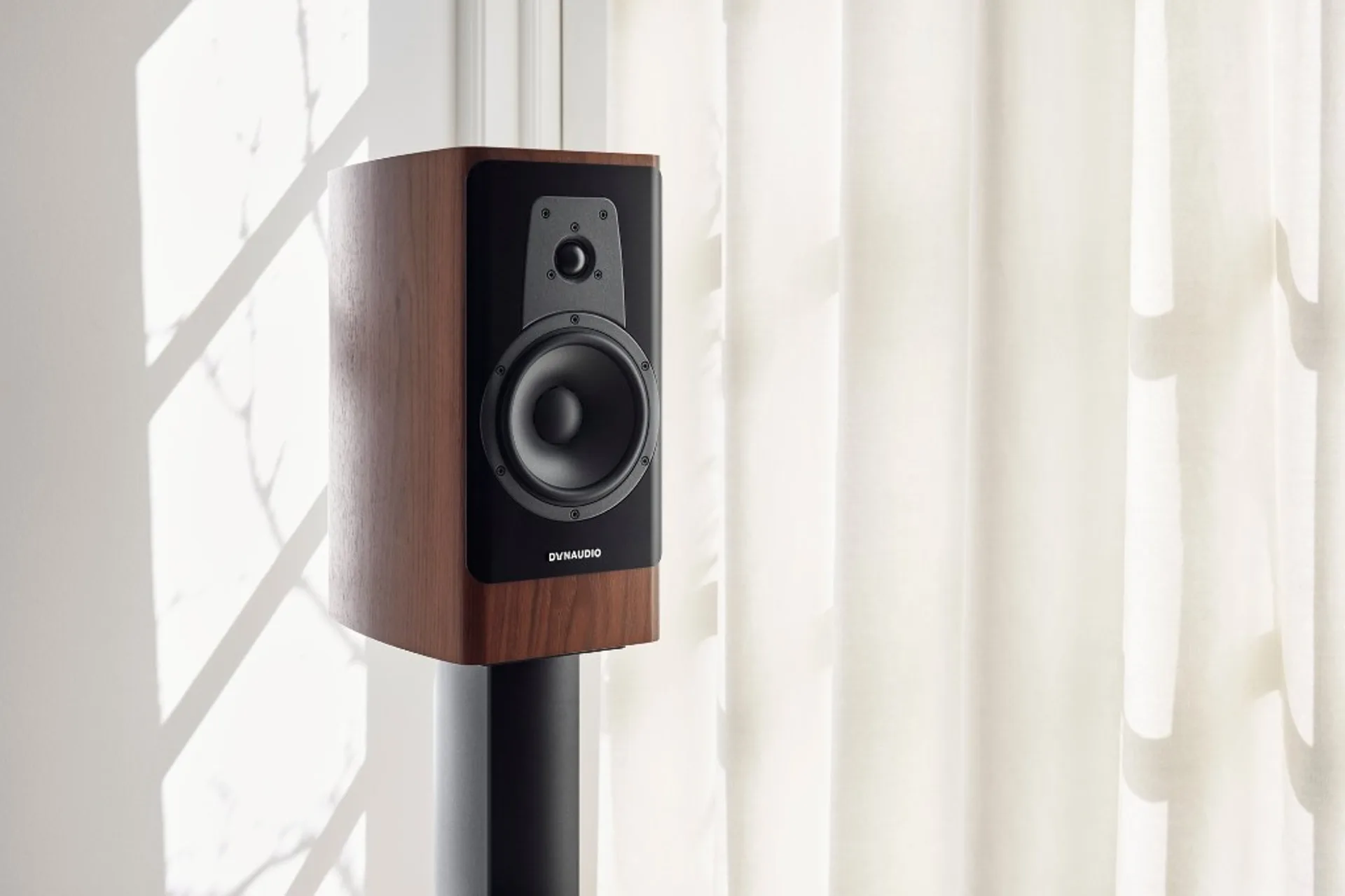 Dynaudio Contour 20i veneer óc chó trên chân loa, góc phòng sáng bên cửa sổ rèm trắng