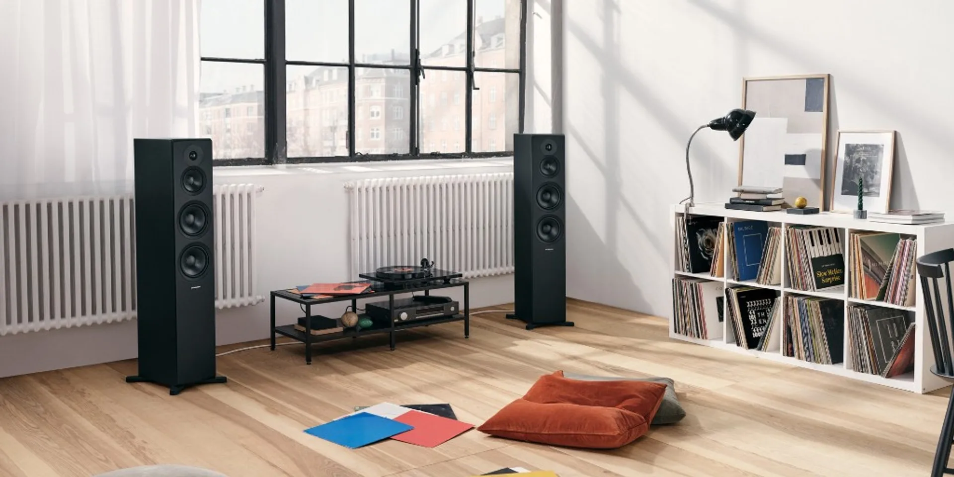 Cặp loa cột Dynaudio Emit 50 đen trong phòng khách sáng, đĩa than và kệ đĩa than vinyl