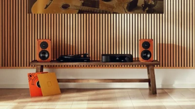 Pair of Dynaudio Heritage Special walnut bookshelf speakers flanking a turntable and MOON integrated amplifier on a rustic b…