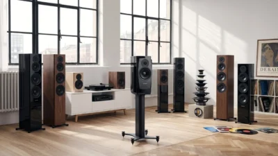 Nhiều loa Dynaudio bookshelf và floorstanding trong phòng sáng sàn xương cá, cửa sổ lớn, bàn console trắng với đĩa than và ampli