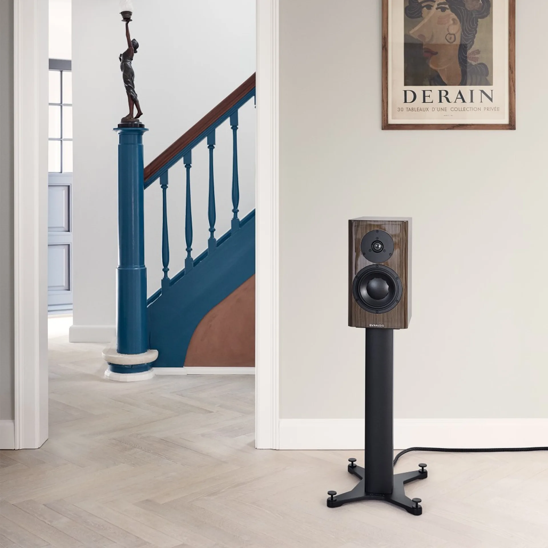 Dynaudio Special Forty veneer Ebony Wave trên chân loa đen, phòng hiện đại sàn xương cá, poster triển lãm Derain và cầu thang xanh cobalt