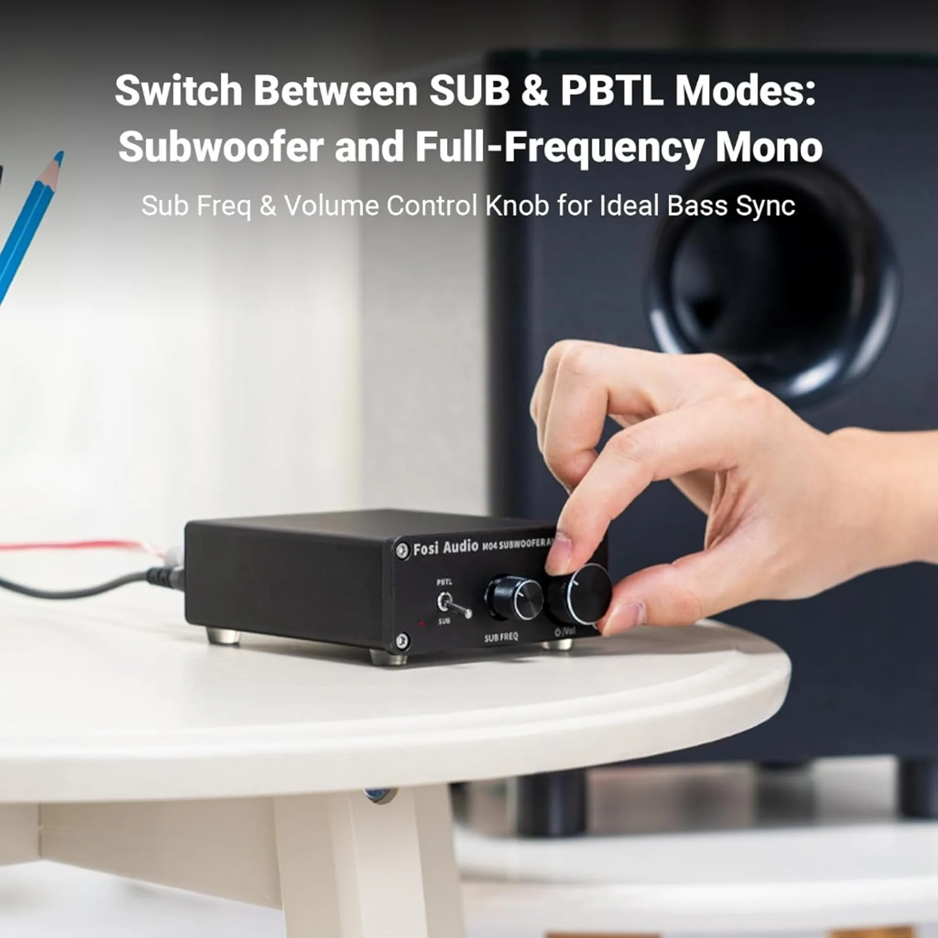 Fosi Audio M04 subwoofer amplifier on white table: hand adjusts volume knob, PBTL and SUB mode switch, sub freq control, bla…