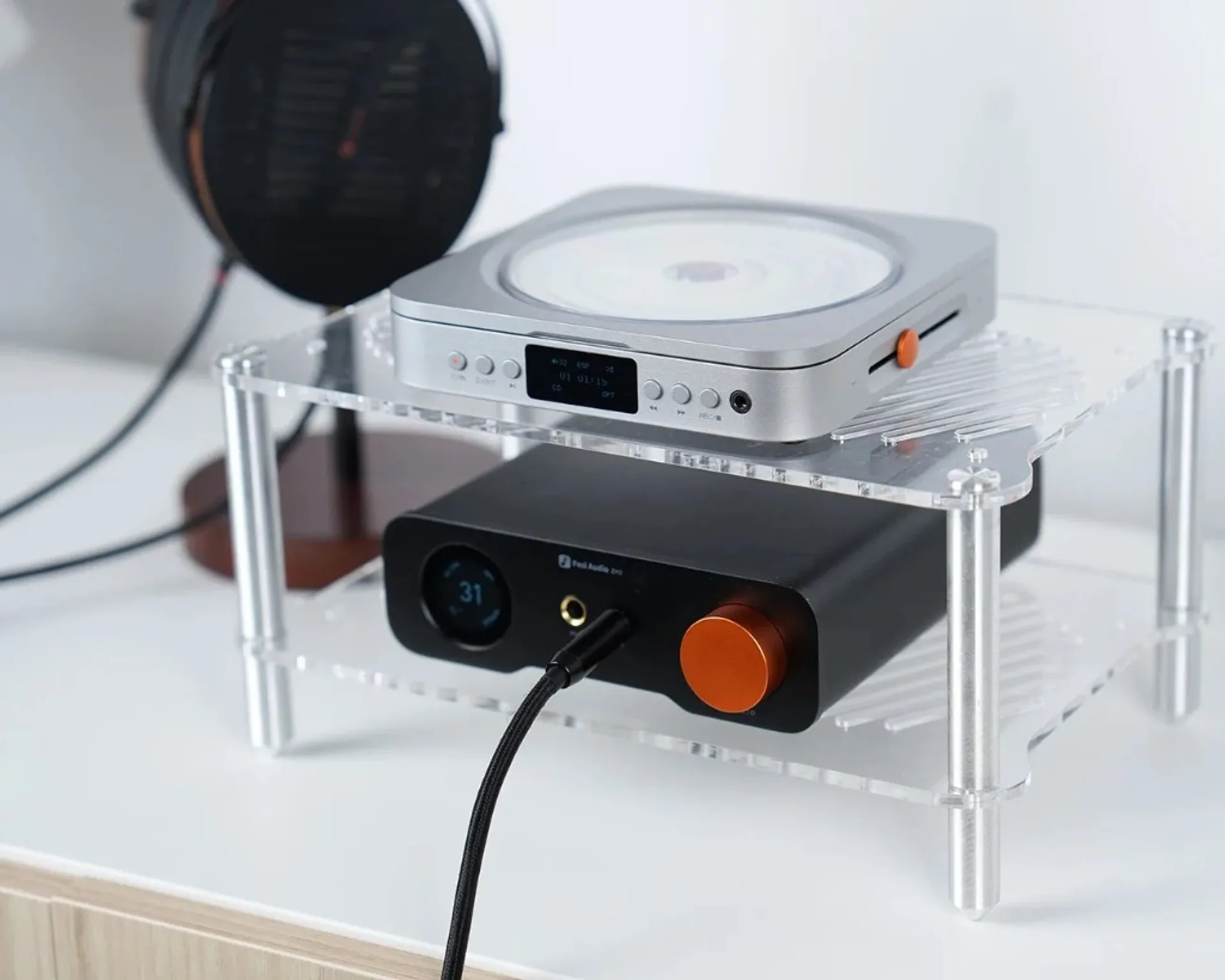 Fosi Audio Merak top-loading CD player on a clear acrylic rack above a Fosi black headphone amp with orange volume knob, pla…
