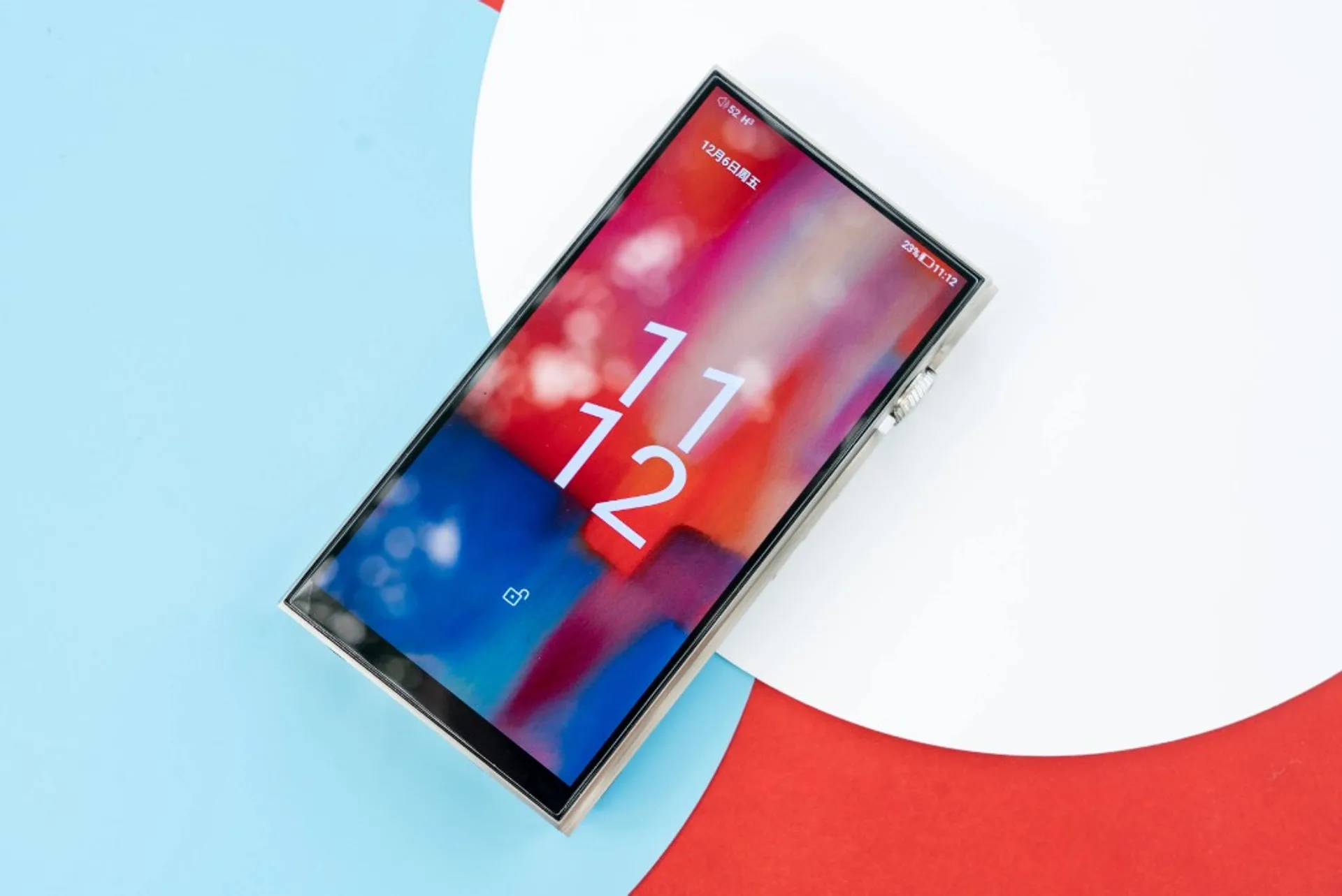 iBasso DX340 digital audio player on colorful geometric background showing lock screen and metallic frame.