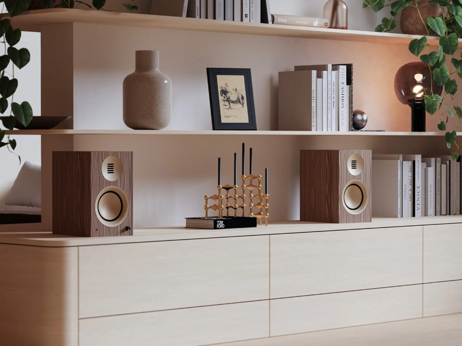 Pair of Kanto TUK Grand speakers in walnut and gold on a light wood sideboard with shelves, books, and plants.
