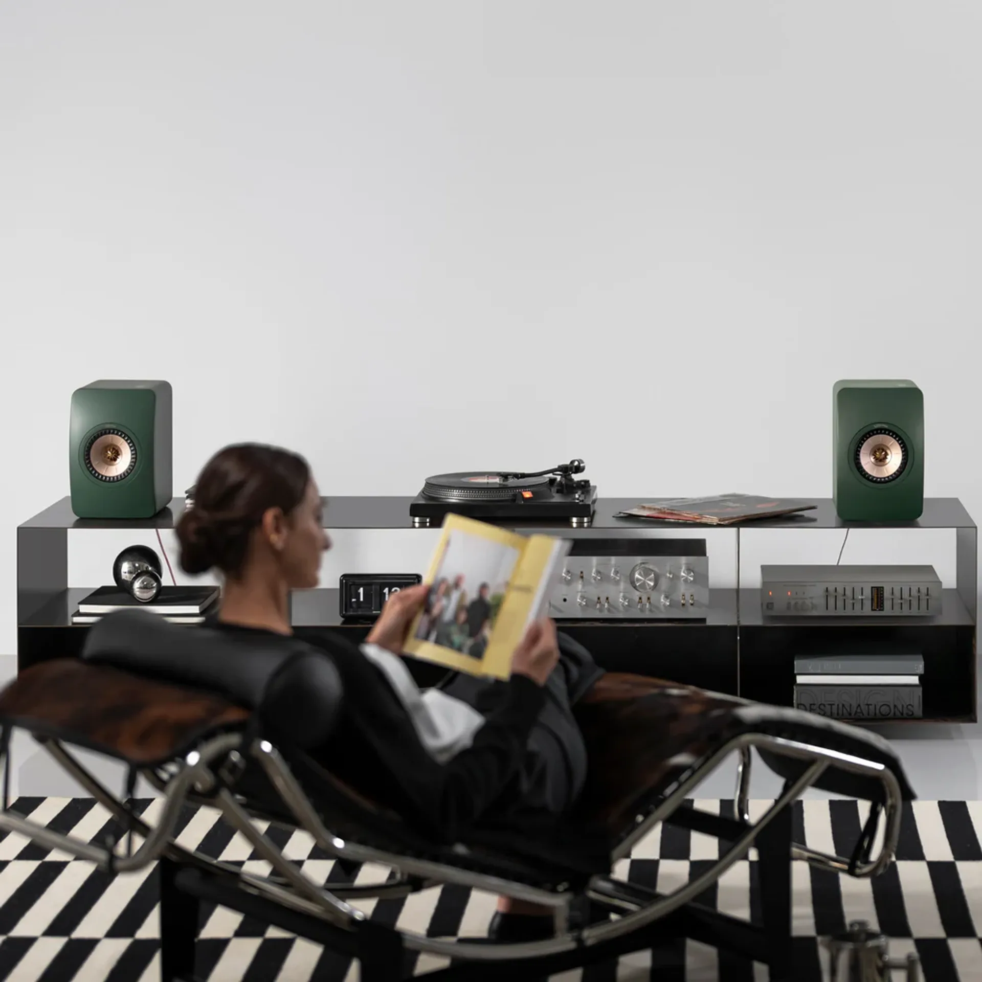 Stereo bookshelf speakers on a shelf with turntable and two-channel hi-fi components.