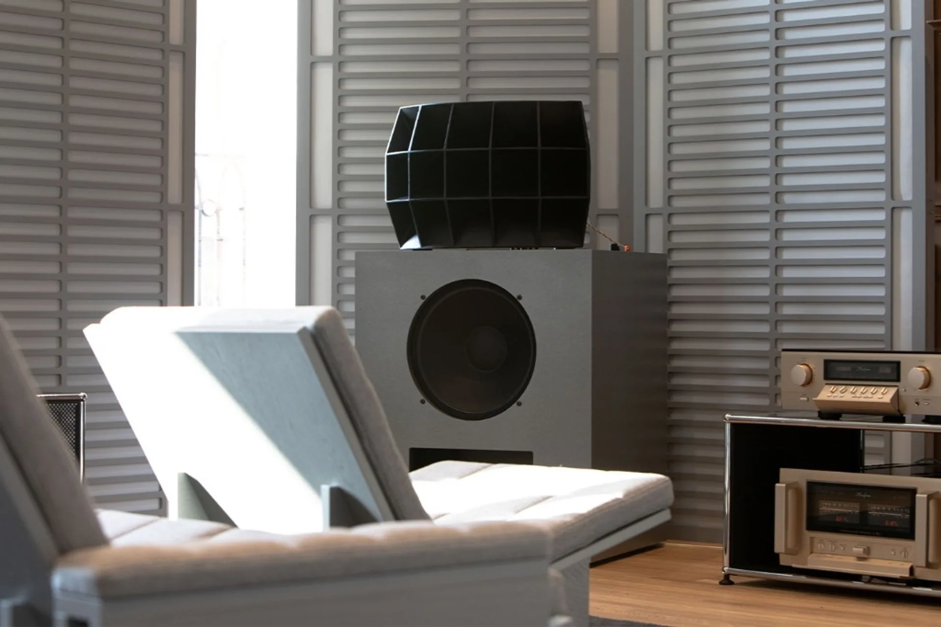 Klipsch Ojas kO-R2 loudspeaker with grey textured bass cabinet, large multicell horn, and copper wiring in a minimalist livi…