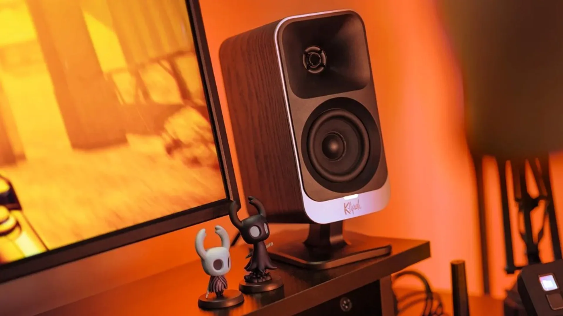 Klipsch ProMedia Lumina satellite speaker on a desktop setup with warm ambient lighting.