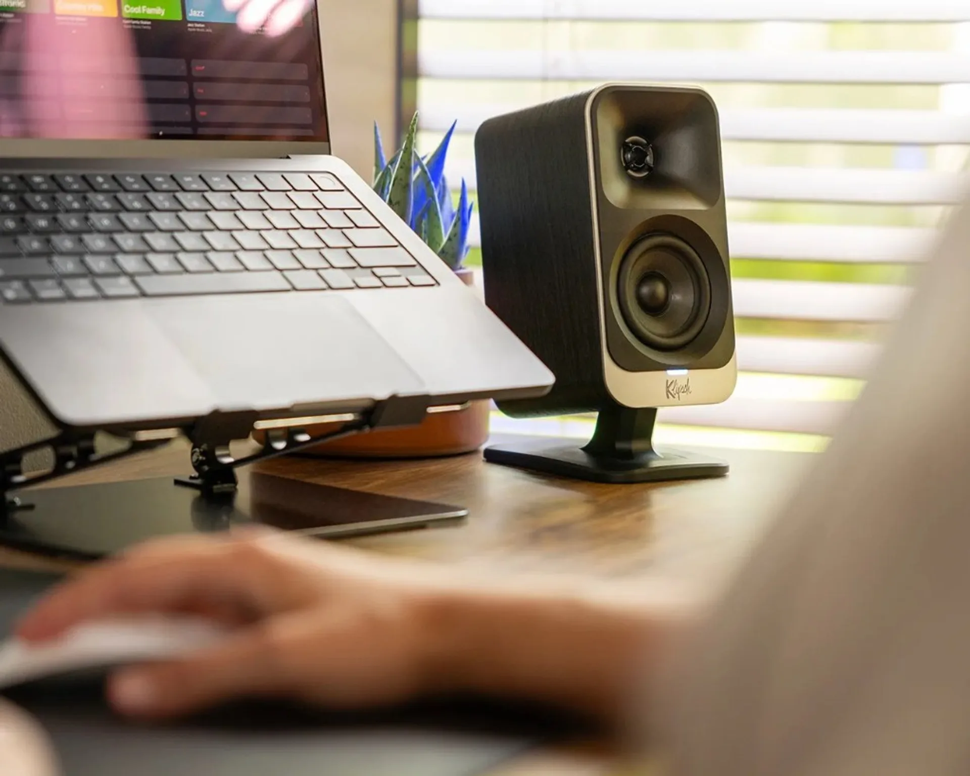 Single Klipsch ProMedia Lumina speaker beside a monitor in a warm-lit gaming desk scene.