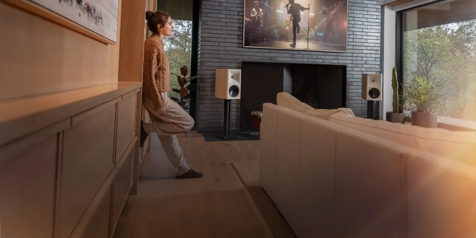 Phòng khách với Klipsch The Nines trên chân loa, TV hiển thị concert, không gian ấm