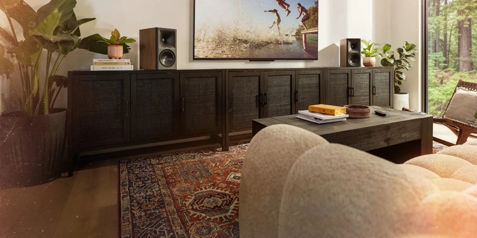 Phòng khách với Klipsch The Sevens hai bên TV, kệ media gỗ tối và thảm trang trí