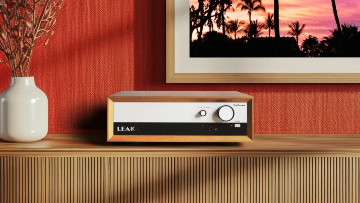 LEAK TruStream network streamer in walnut wood case on a slatted wooden credenza, red textured wall, palm sunset art, headph…