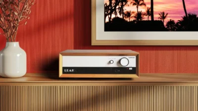 LEAK TruStream network streamer in walnut wood case on a slatted wooden credenza, red textured wall, palm sunset art, headph…