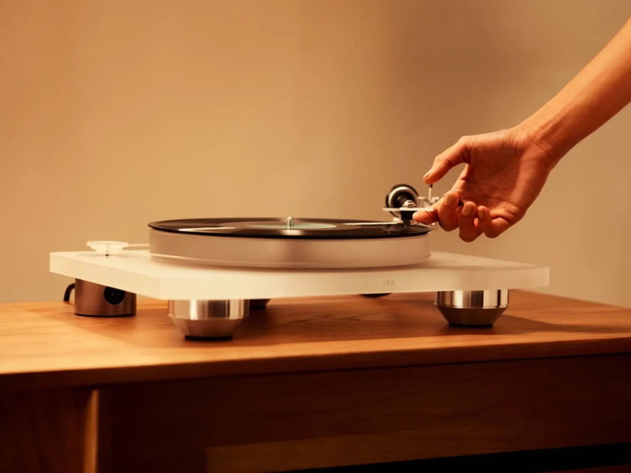 Marantz TT-15S1 nhìn nghiêng thân acrylic mờ, tay chạm gần tonearm trên mặt gỗ
