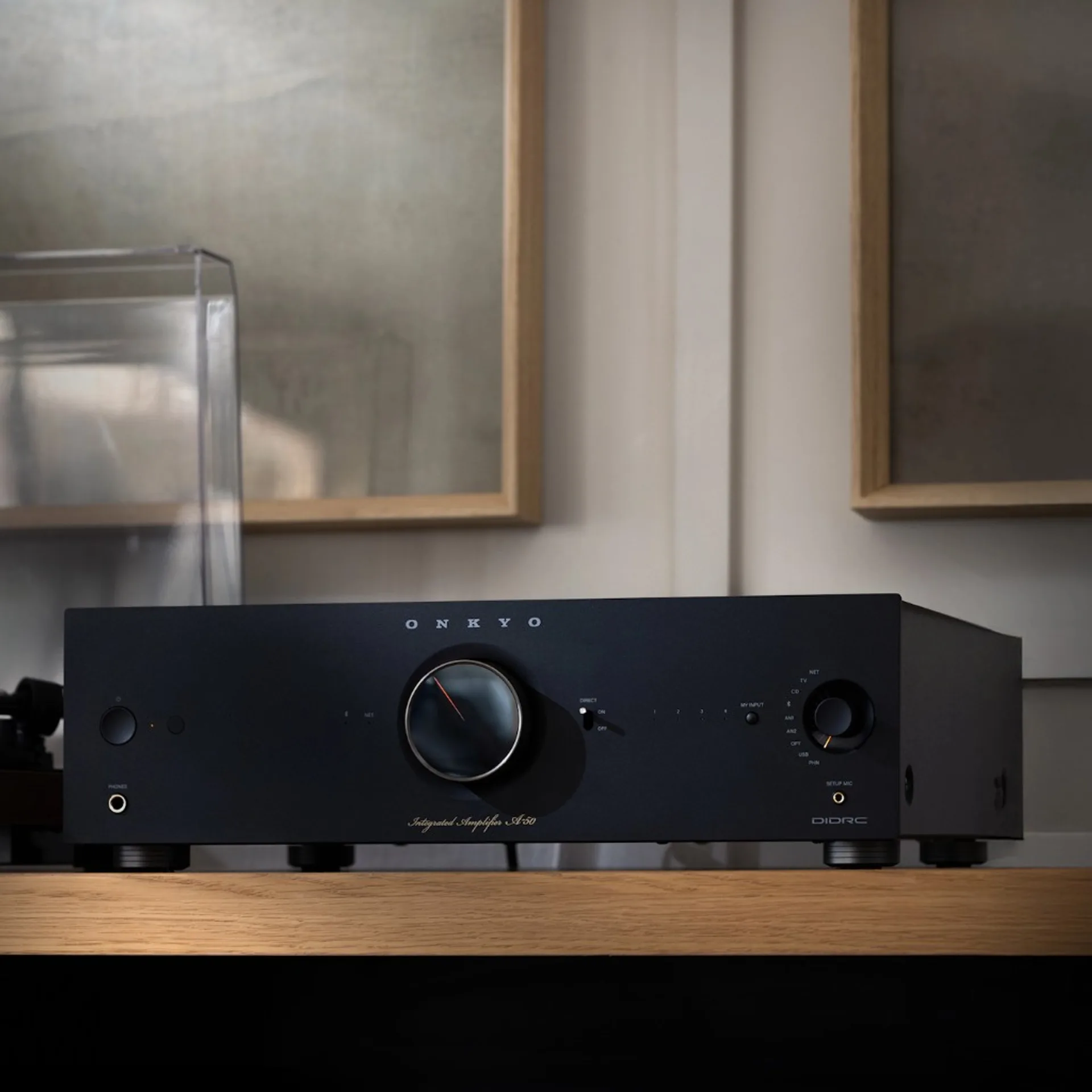 Matte black Onkyo Icon A-50 integrated amplifier on a wood shelf beside a turntable with clear dust cover.