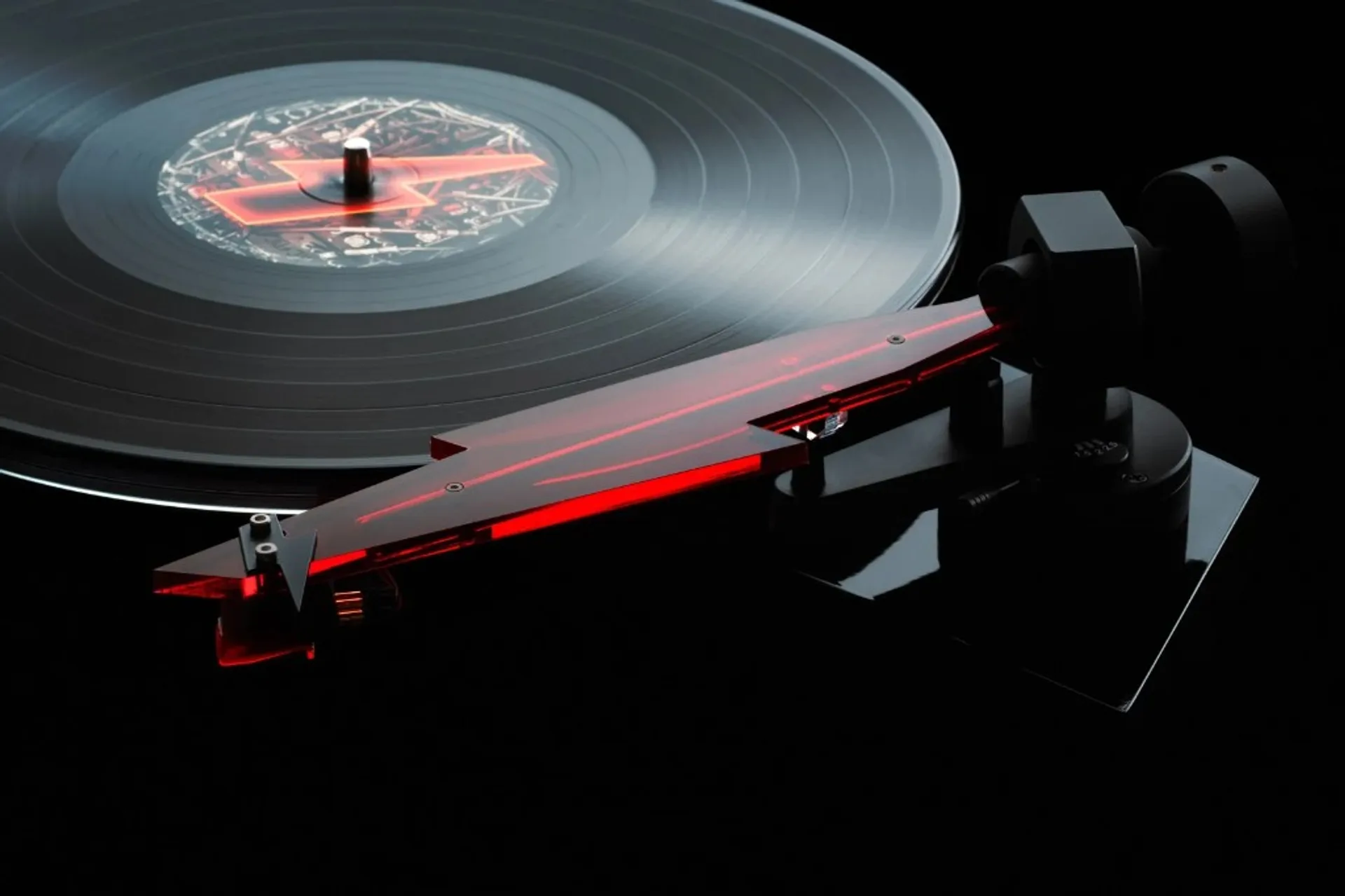 Close-up of Pro-Ject AC/DC turntable translucent red lightning-bolt tonearm over a vinyl record on a dark background.