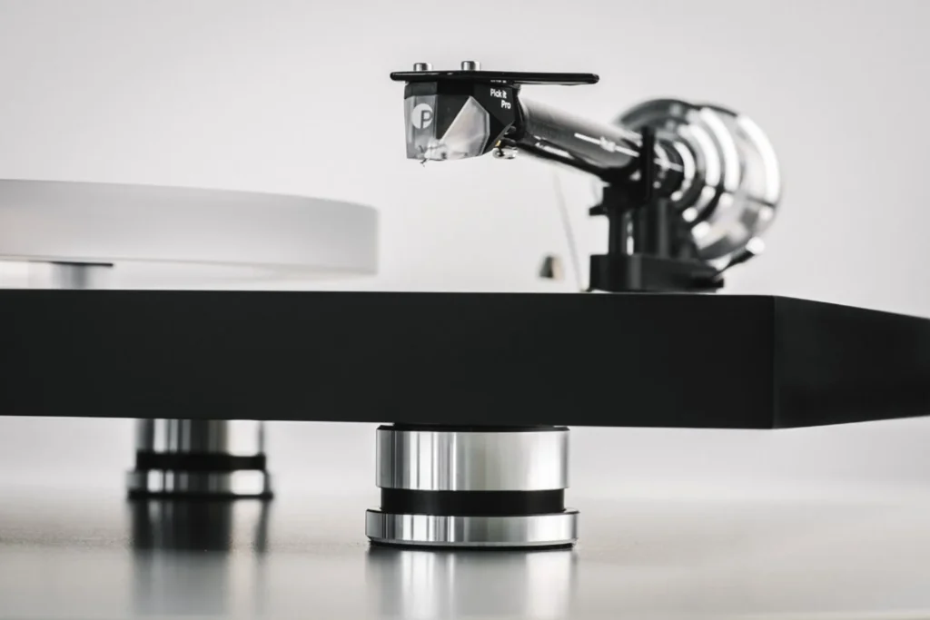 Close-up side view of a Pro-Ject Debut Reference 10 turntable: Pick it Pro cartridge on carbon tonearm, matte black plinth,…