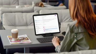 Lifestyle photo of user typing on tablet connected to Satechi OntheGo Foldable Stand Hub in an airport lounge.