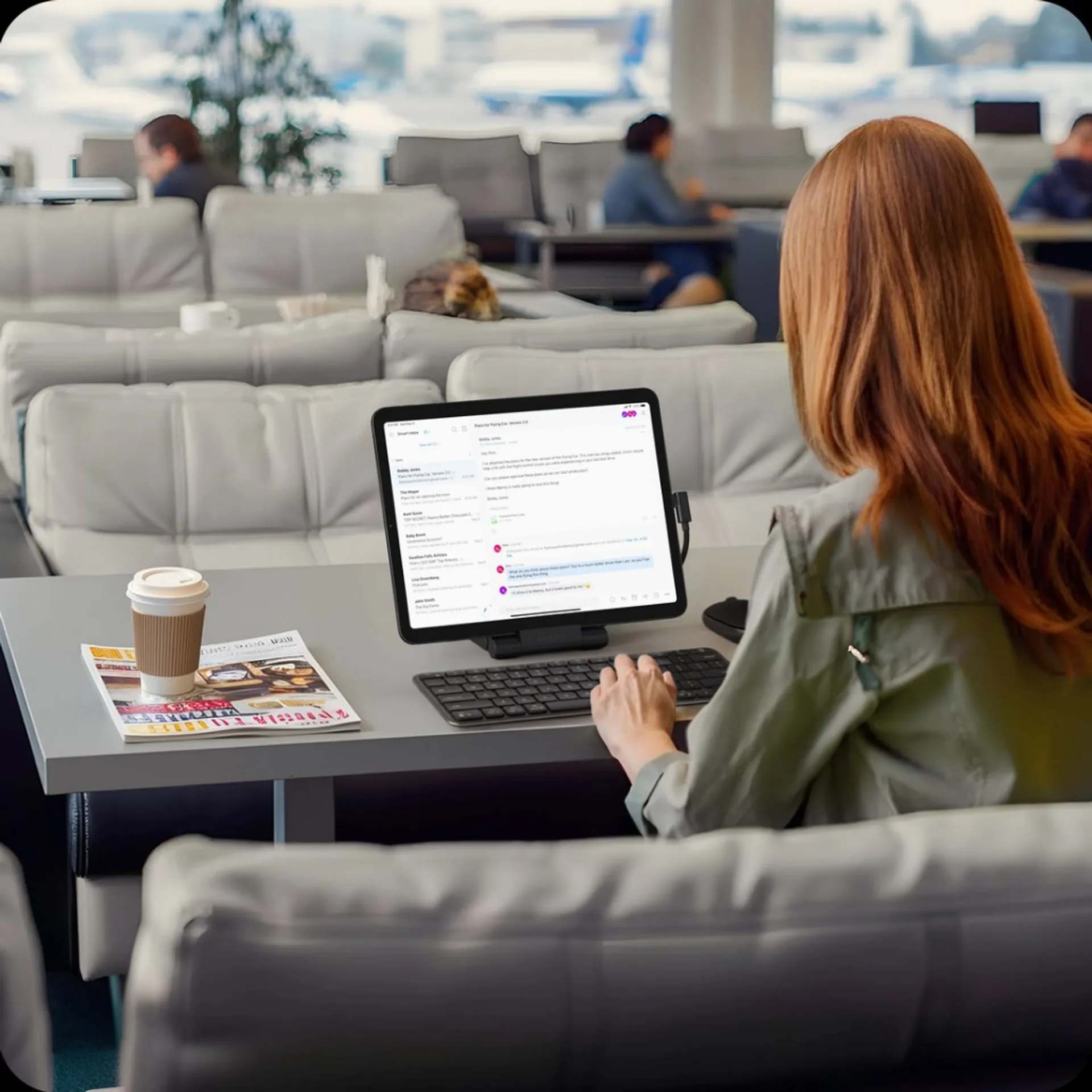 Lifestyle photo of user typing on tablet connected to Satechi OntheGo Foldable Stand Hub in an airport lounge.