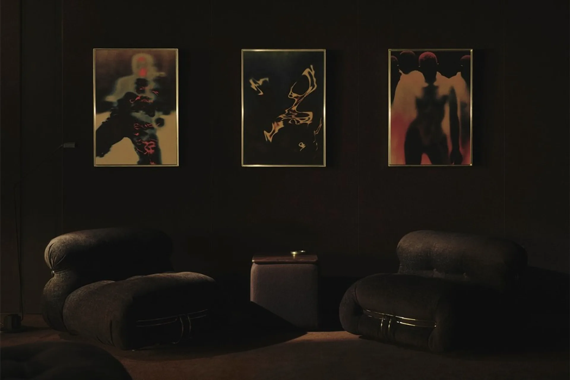 Dark lounge with three gold-framed abstract artworks and paired designer armchairs, Spotify Listening Lounge London.