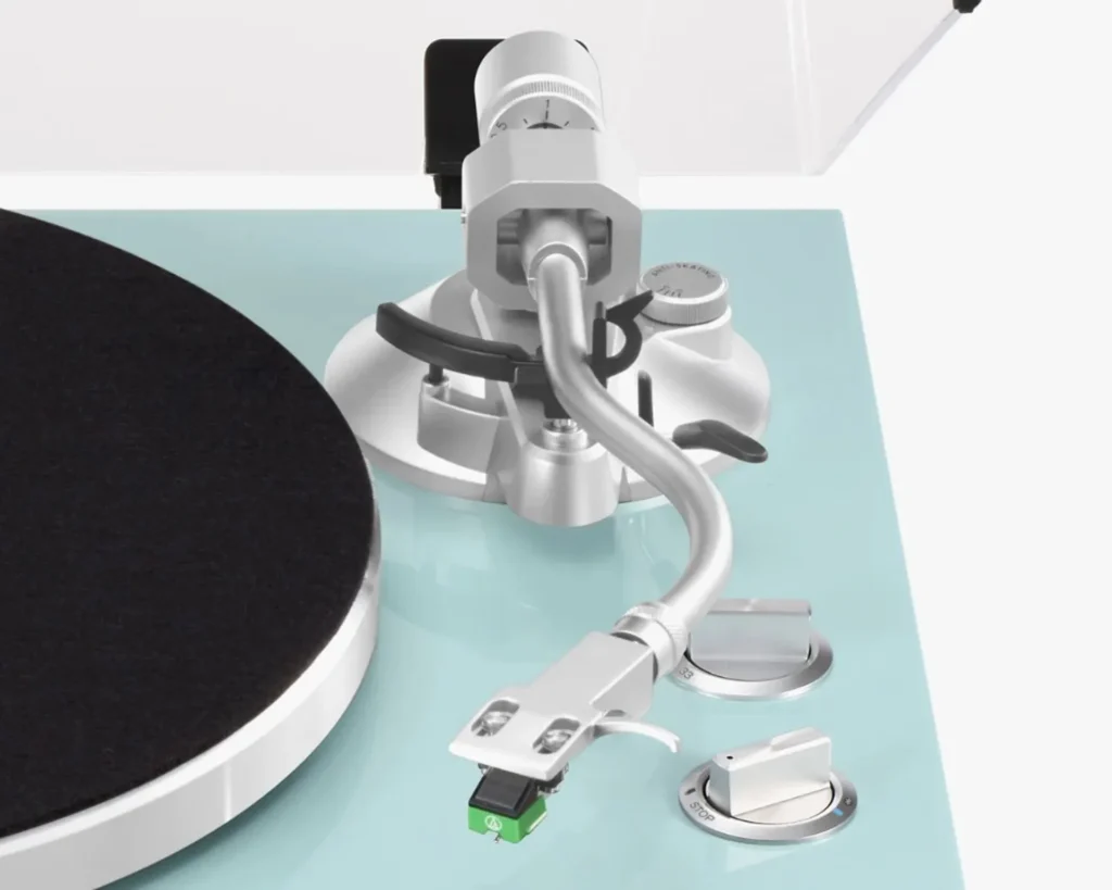 Close-up of TEAC TN-400BT-X: S-tonearm with green stylus cartridge, anti-skate and cue lever, speed and start-stop knobs on…