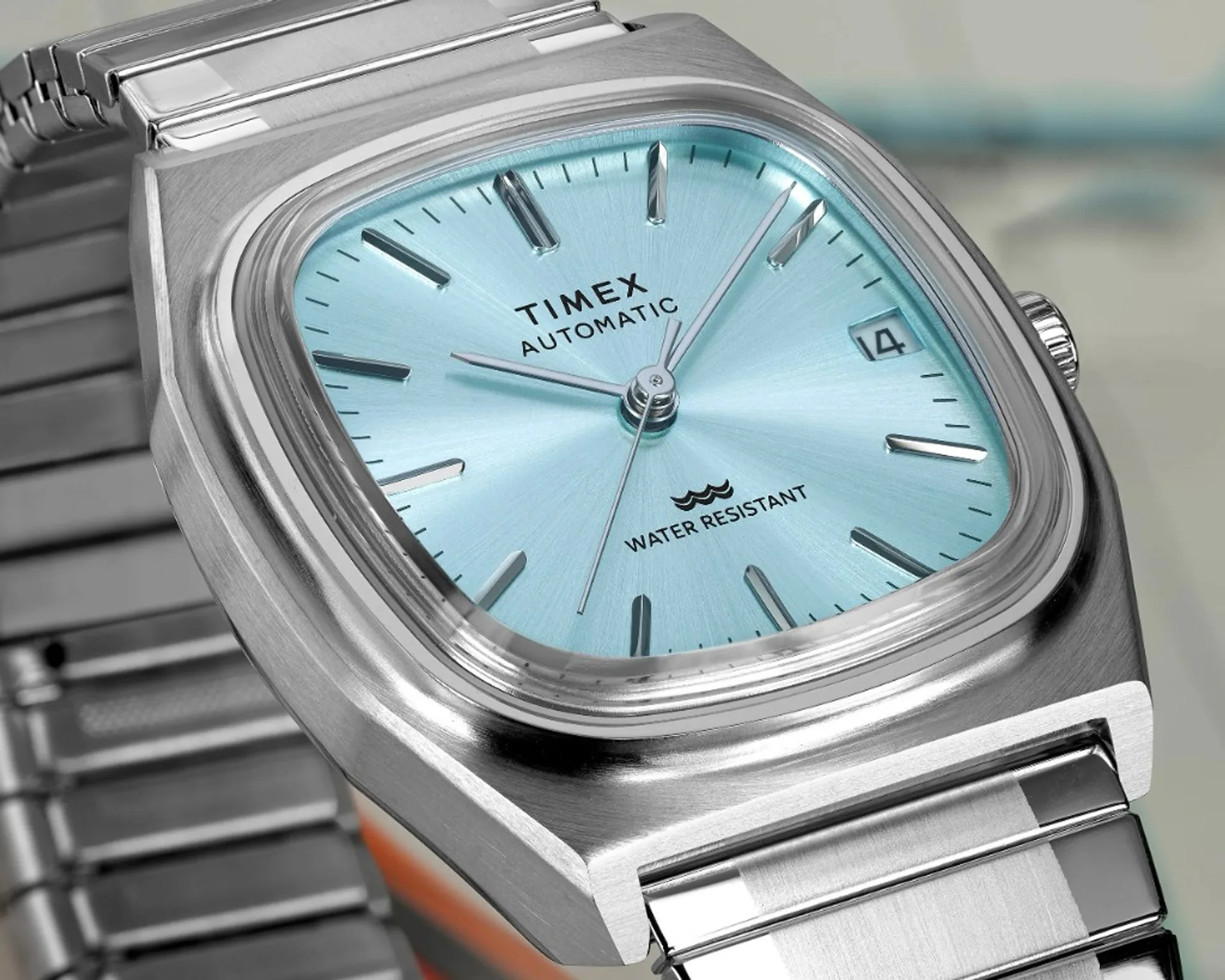 Close-up of Timex Automatic 1983 E Line ice blue sunburst dial, silver hands, domed crystal, brushed TV-dial stainless steel case.