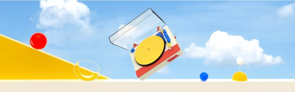 Tinyl Play Pro turntable in a surreal Memphis-style scene: cream, red, and yellow deck tilted against a bright blue sky with…
