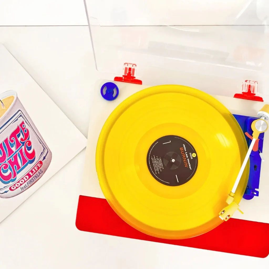 Top-down view of Tinyl Play Pro with red, blue, and yellow accents playing a translucent yellow John Lee Hooker Burnin vinyl…