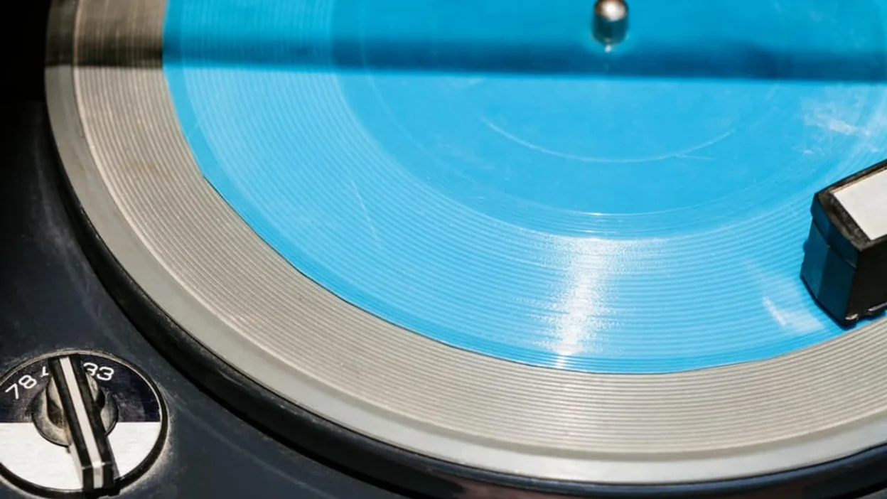 Close-up of vintage turntable with cyan blue vinyl and 33/45/78 RPM speed dial