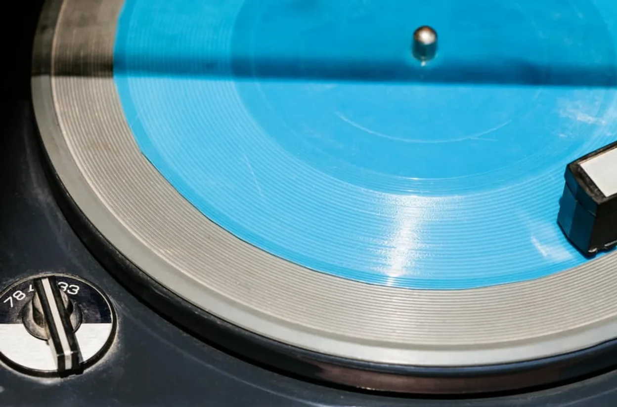 Close-up of vintage turntable with cyan blue vinyl and 33/45/78 RPM speed dial