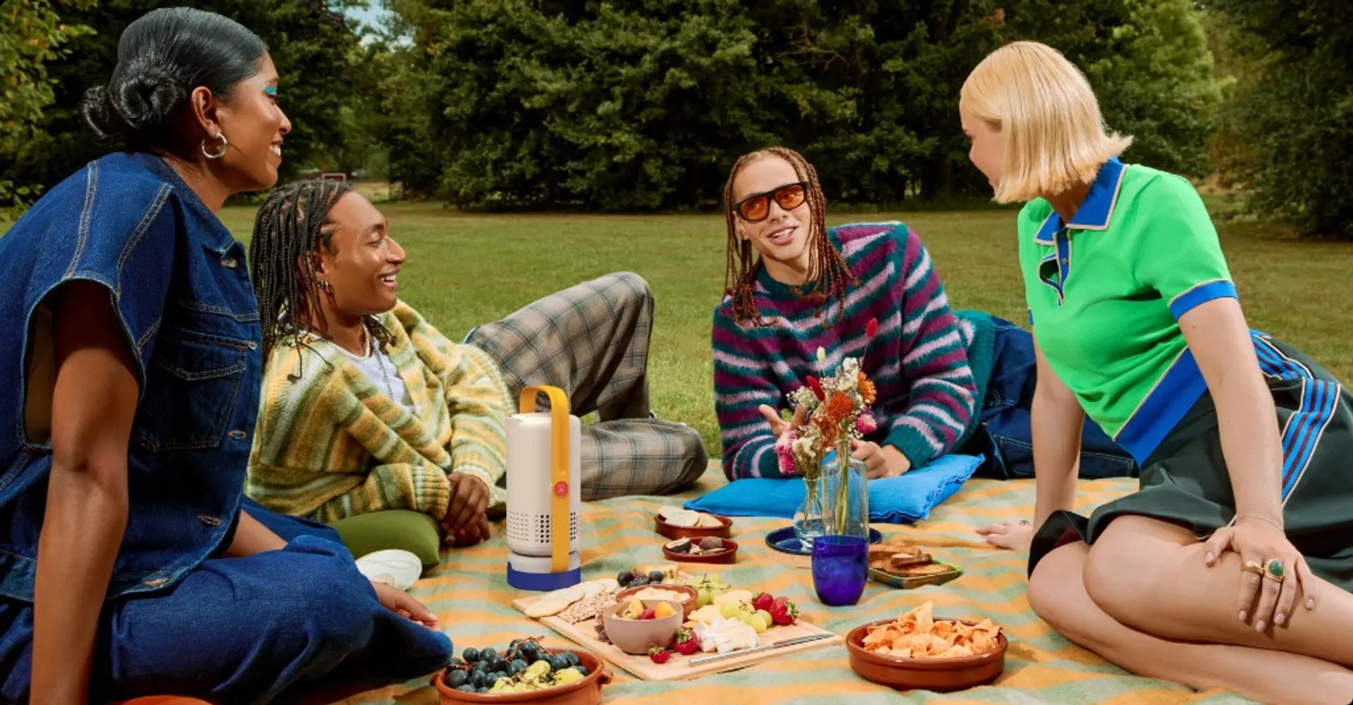 XGIMI Vibe One portable projector on a picnic blanket with friends outdoors in a sunny park, highlighting portability and so…