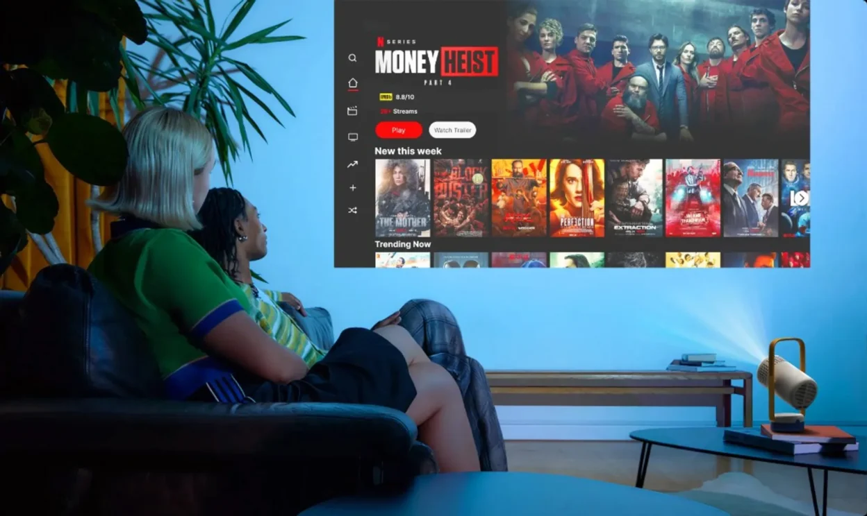 XGIMI Vibe One projecting Netflix on a wall in a dim living room with two people on a sofa watching Money Heist.