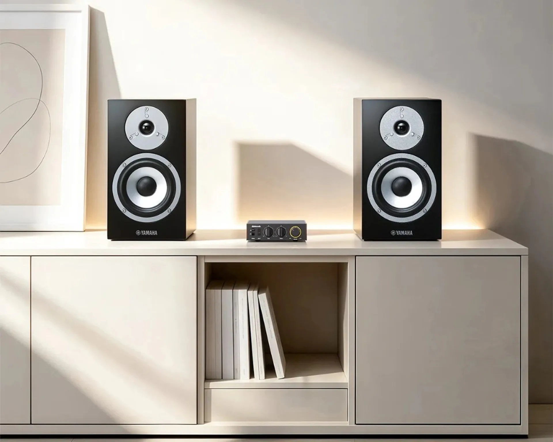 FiiO Jade Audio Level 1 desktop amplifier between two black Yamaha bookshelf speakers on a minimalist white media console.