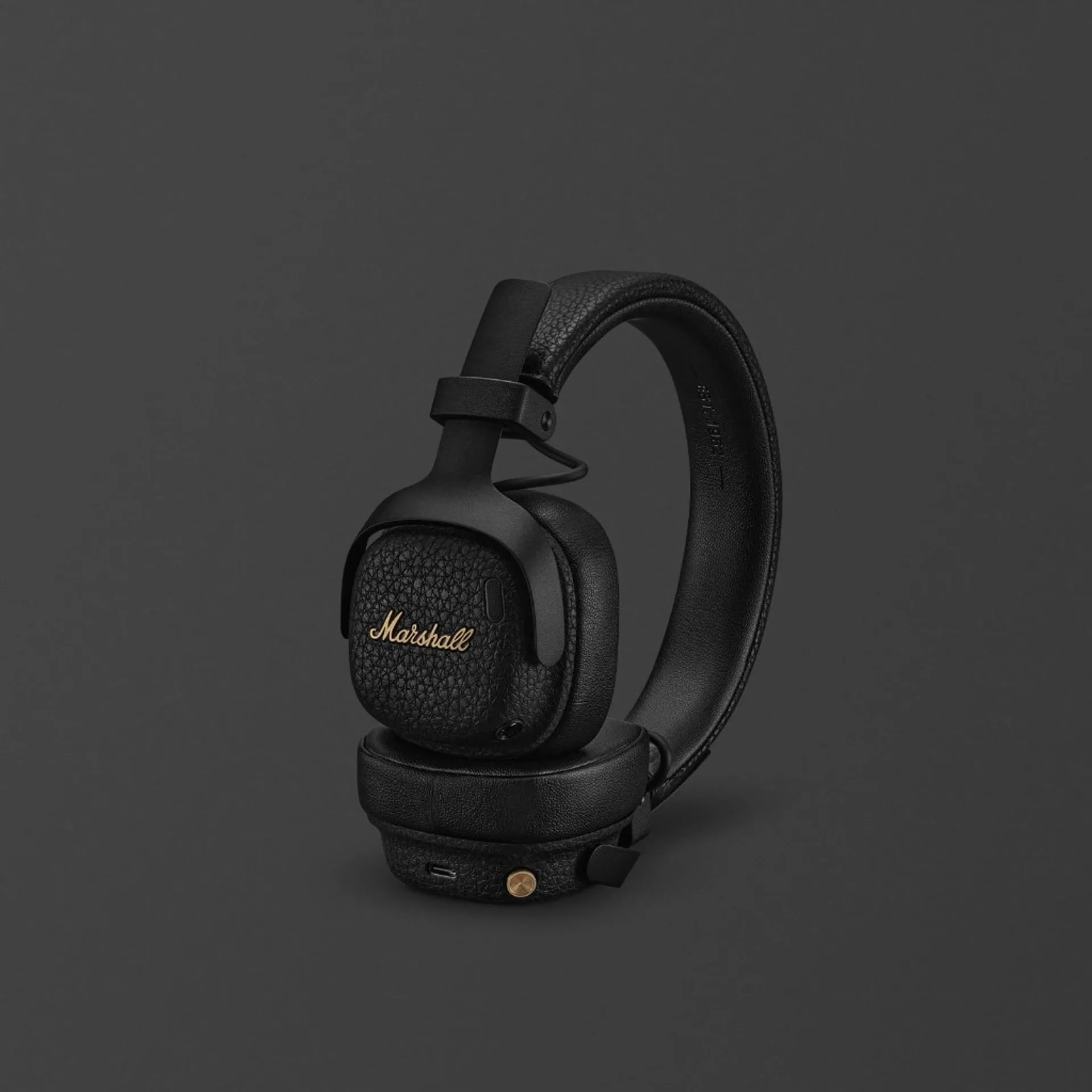 Marshall Milton ANC on-ear headphone in black with gold script logo, textured ear cup, and folding headband on dark grey background.