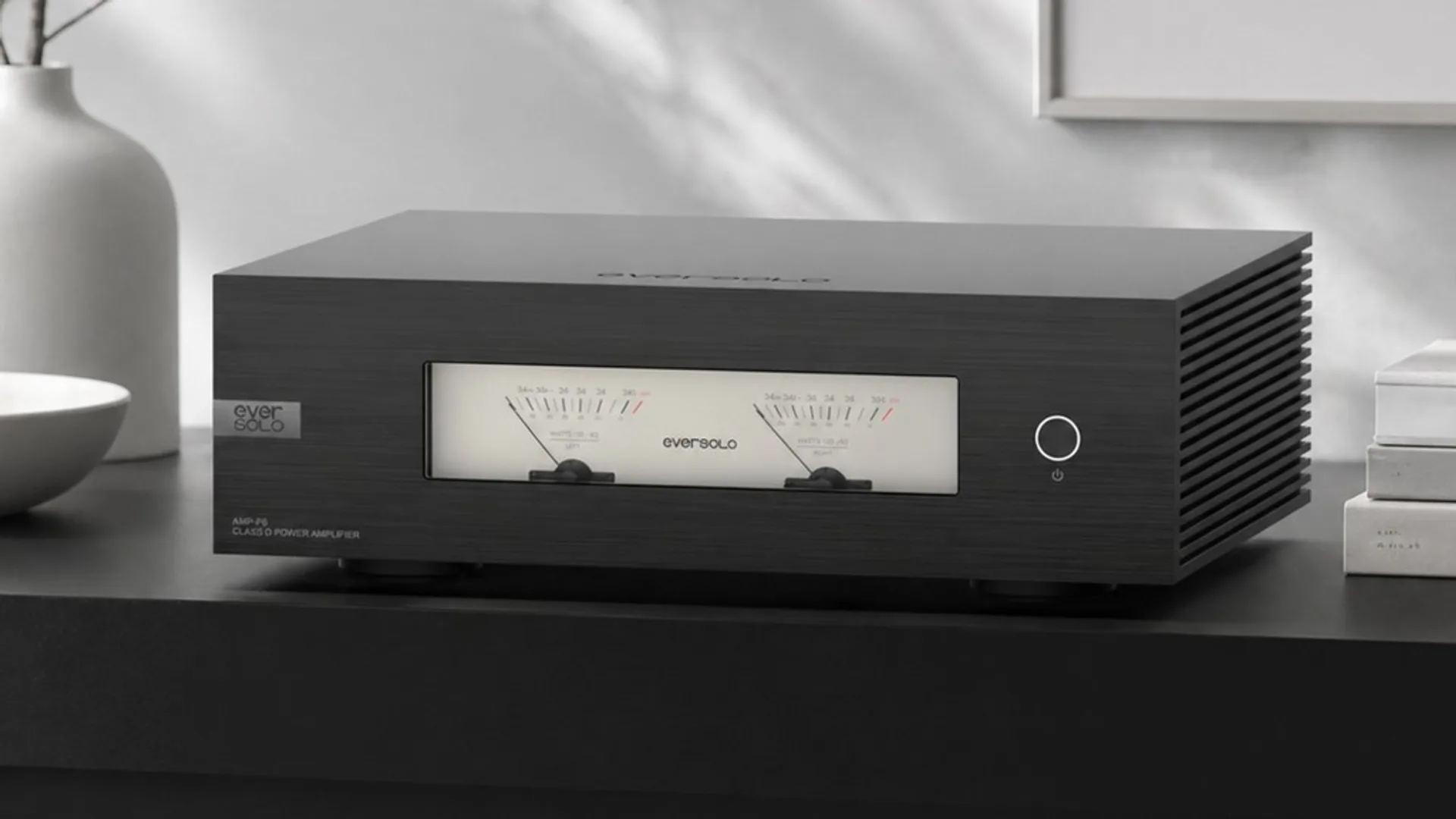 Eversolo AMP-F6 Class D GaN power amplifier with dual analog VU meters in a minimalist home setting.