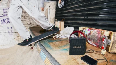 Marshall Stockwell III portable speaker at an indoor skate park connected to a smartphone with skaters in the background.