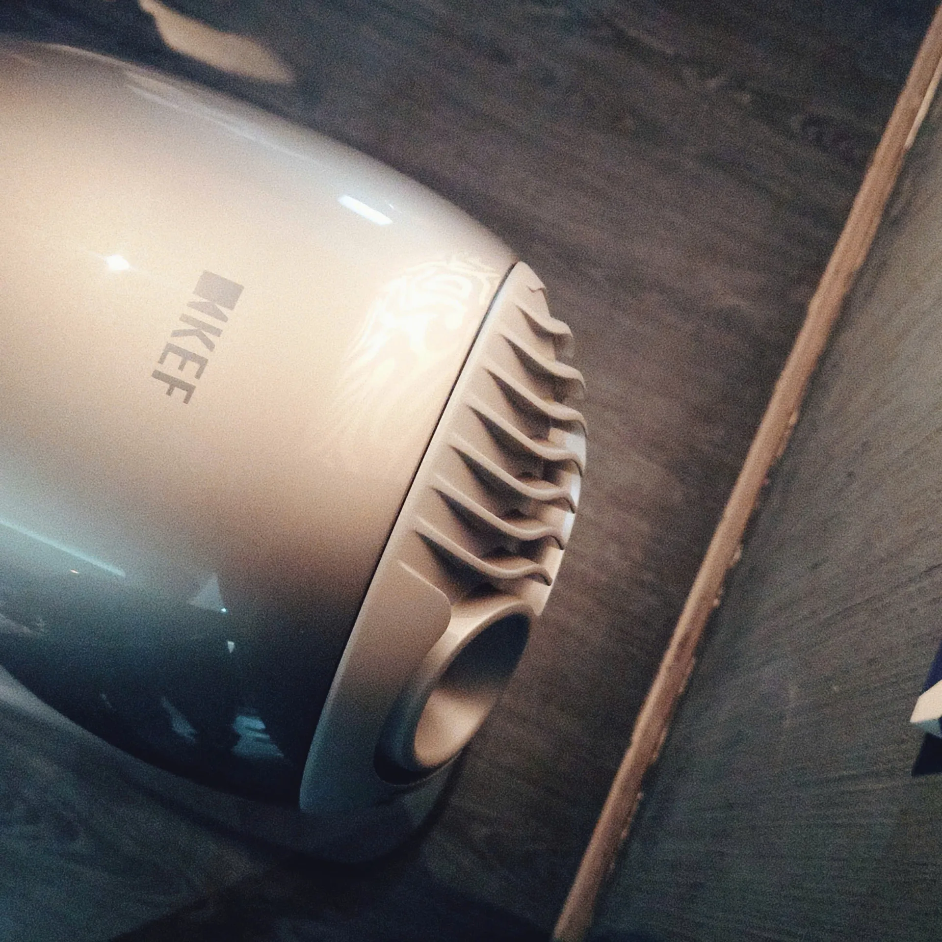 Top rear of KEF LS LUXE showing KEF logo curved heatsink fins and bass reflex port
