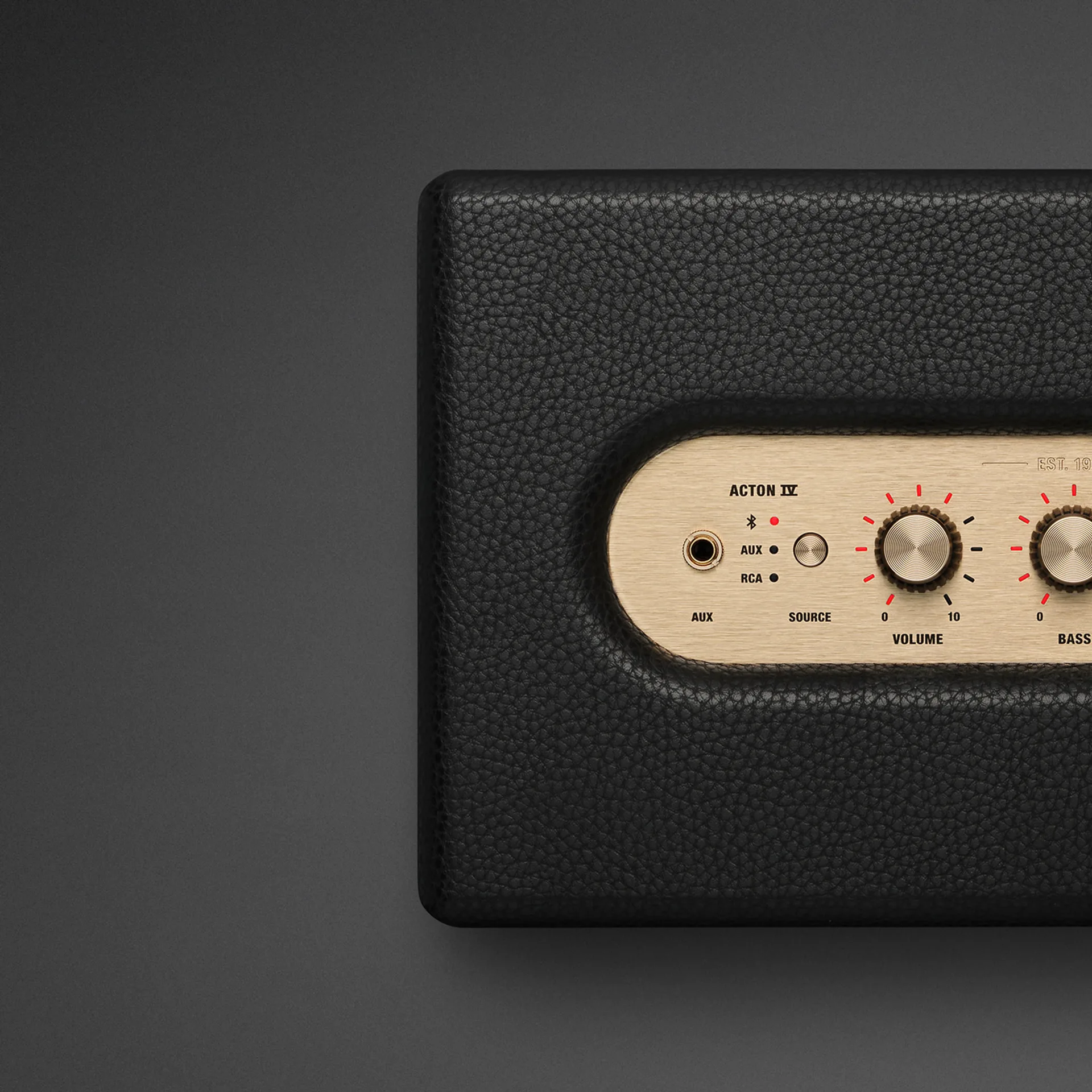 Close-up of Marshall Acton IV brass top panel showing AUX jack, Bluetooth AUX RCA source LEDs, and volume knob.