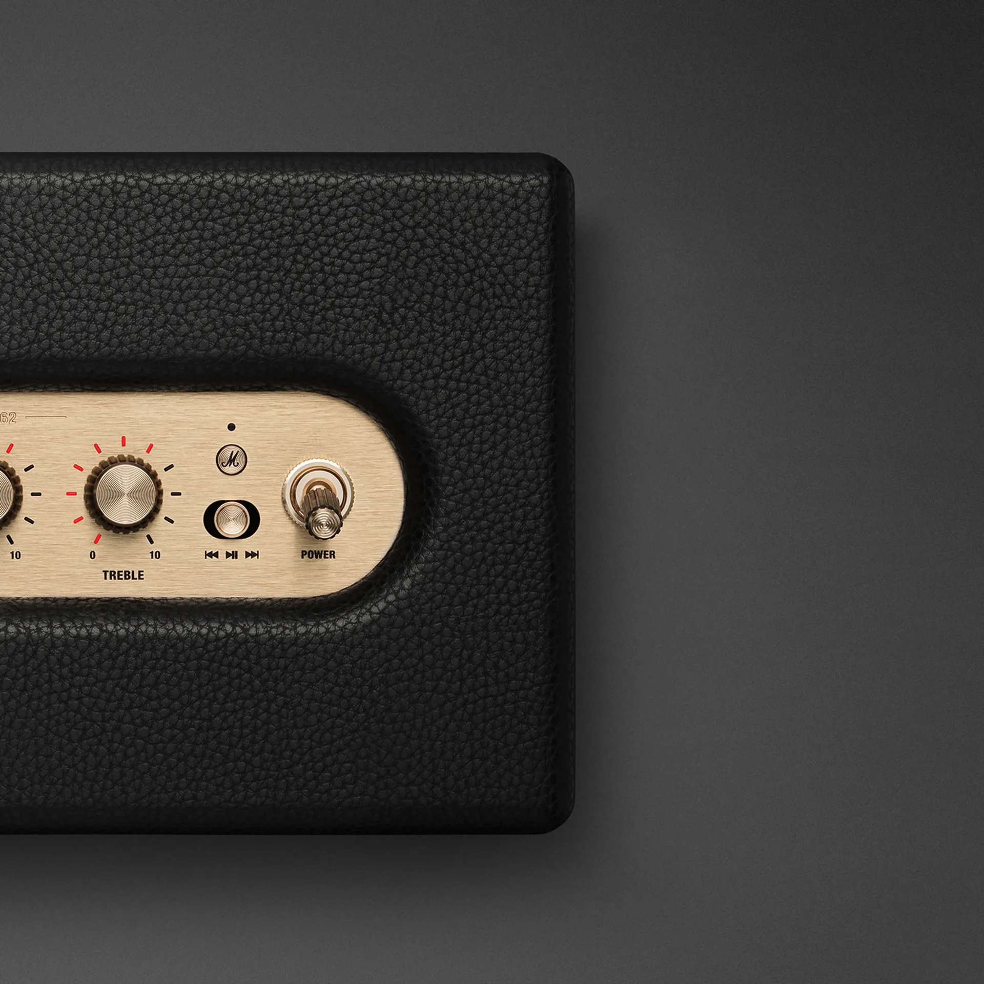 Marshall Acton IV brass control panel close-up with treble knob, M-button, media jog, and power toggle switch.